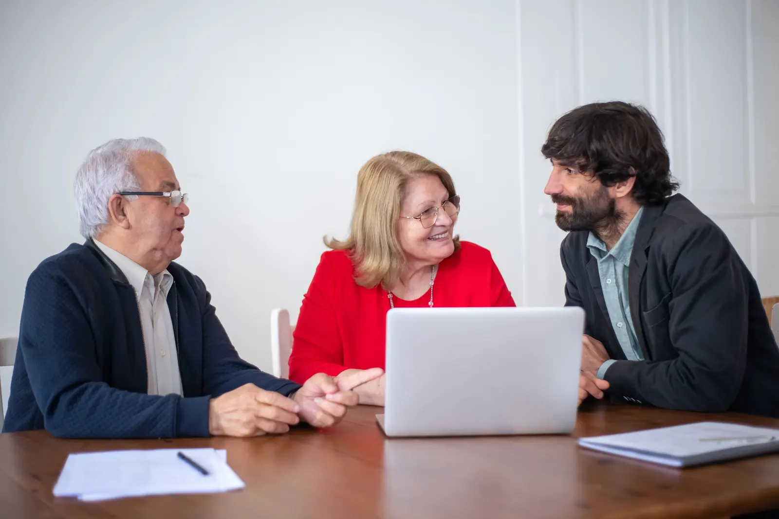 Un consulente al tavolo con una coppia di clienti: parlano sorridendo, con il portatile aperto